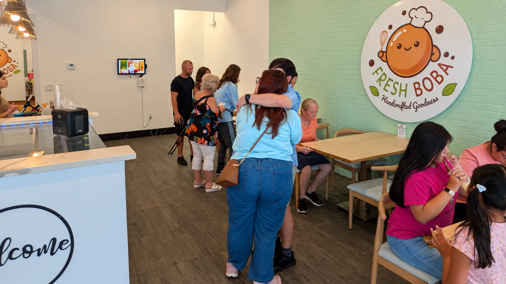 Guests enjoying the FRESH BOBA Bradenton shop during the Grand Reopening celebration, with the FRESH BOBA logo on the wall.